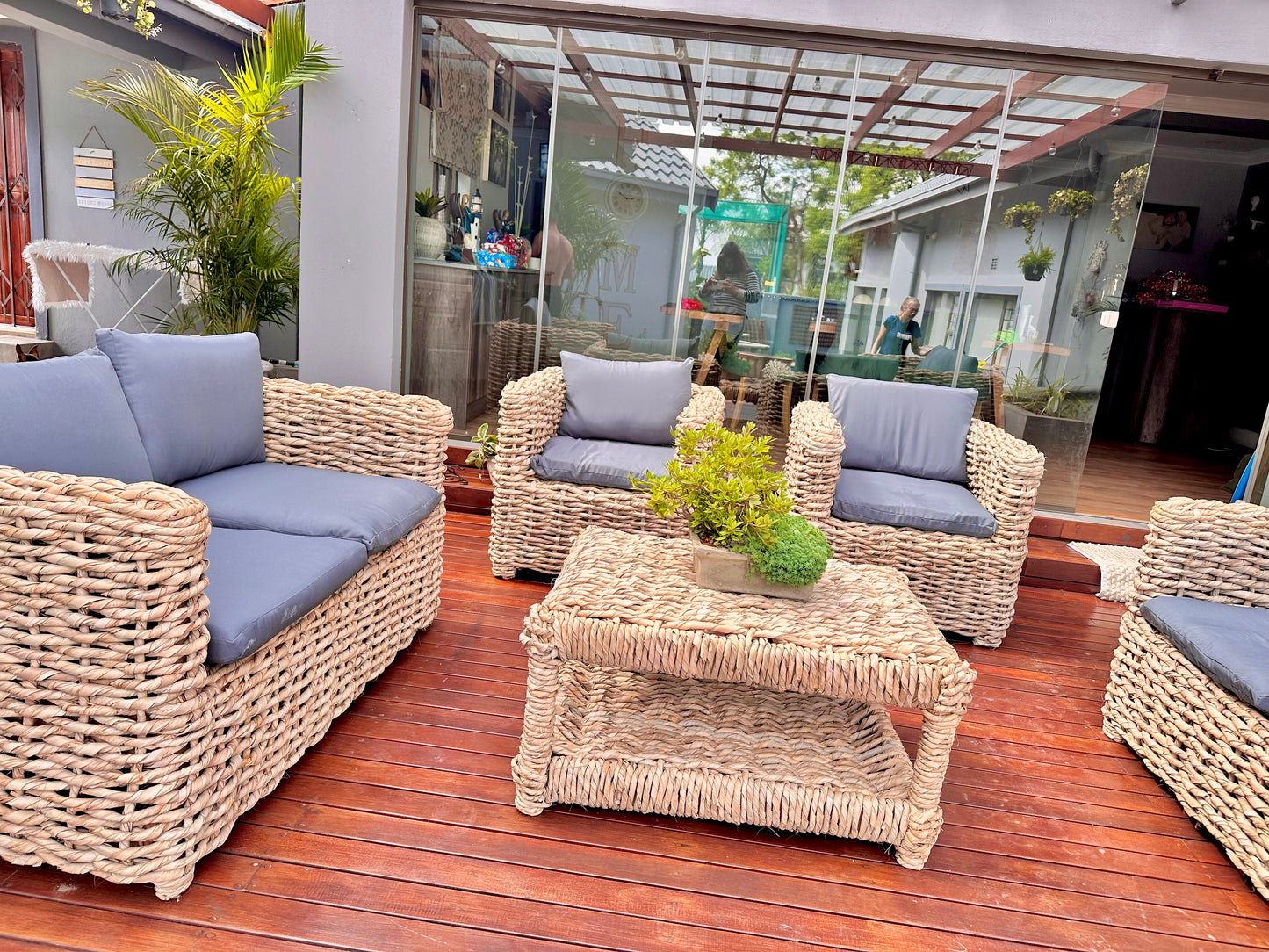 A grey cushion wicker lounge suite that made up of 2 double seaters and 2 single seaters with a coffee table