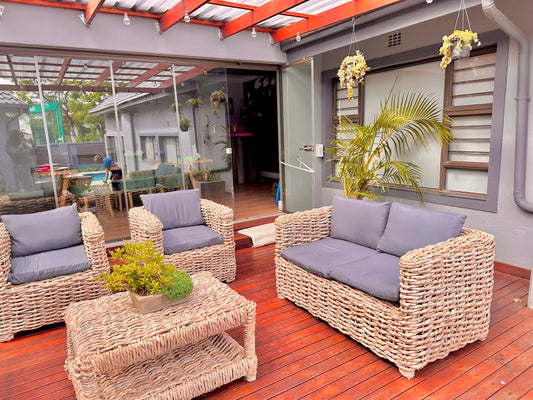 A grey cushion wicker lounge suite that is a double seater and 2 single seaters with a coffee table