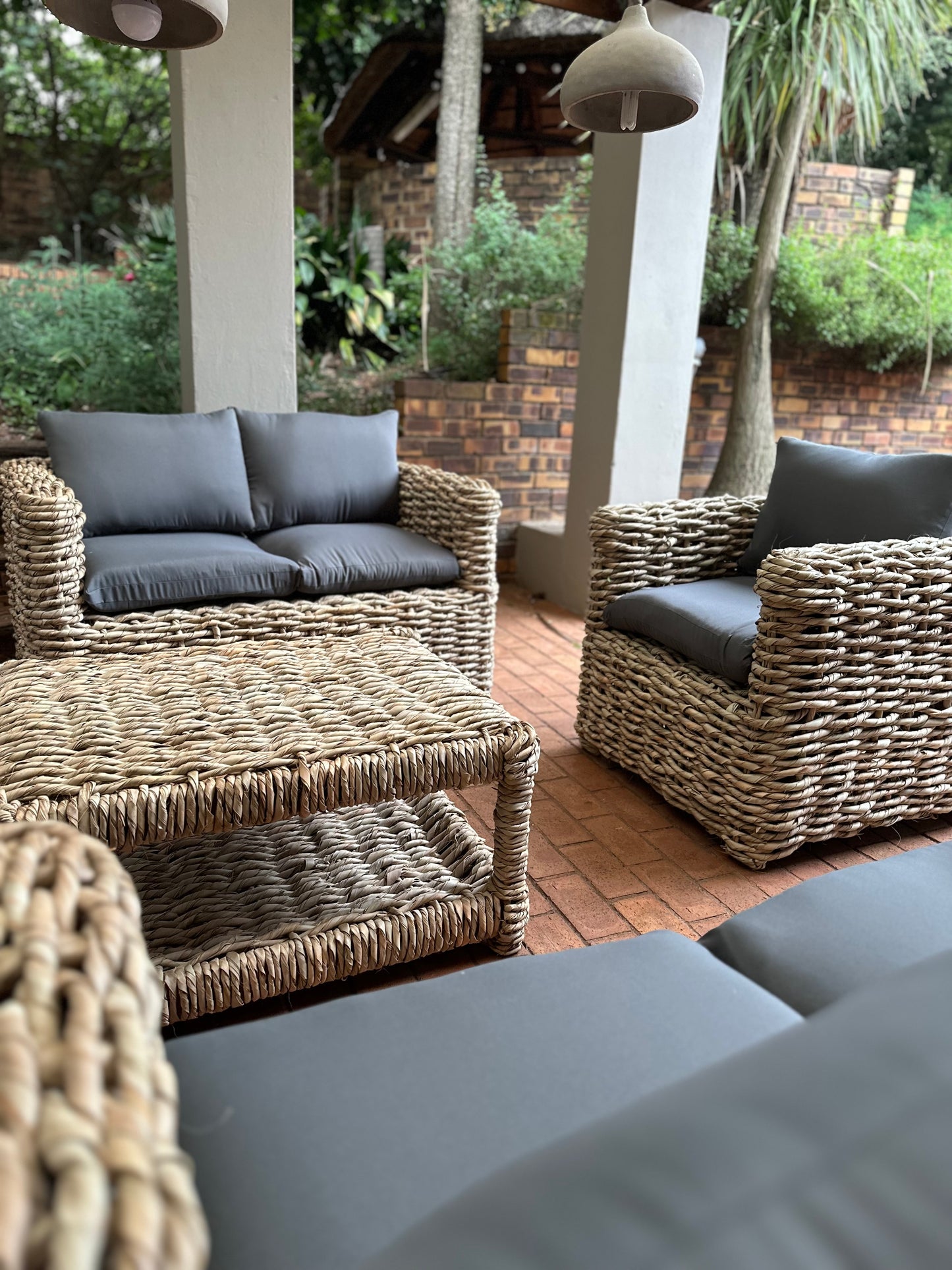 1-seater grey cushion wicker couch with other wicker couches nearby