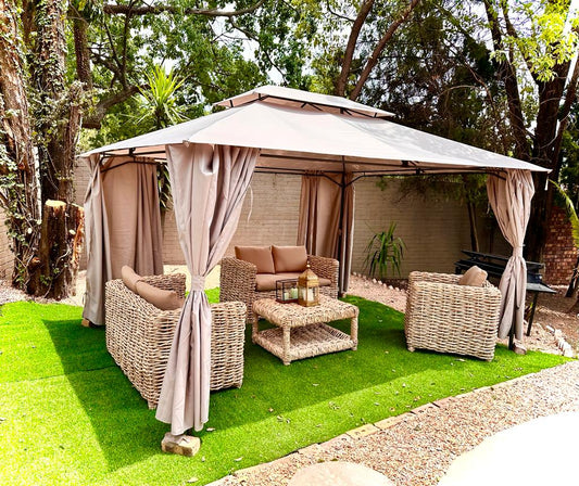 Beige cushion wicker couches under a tent on green grass