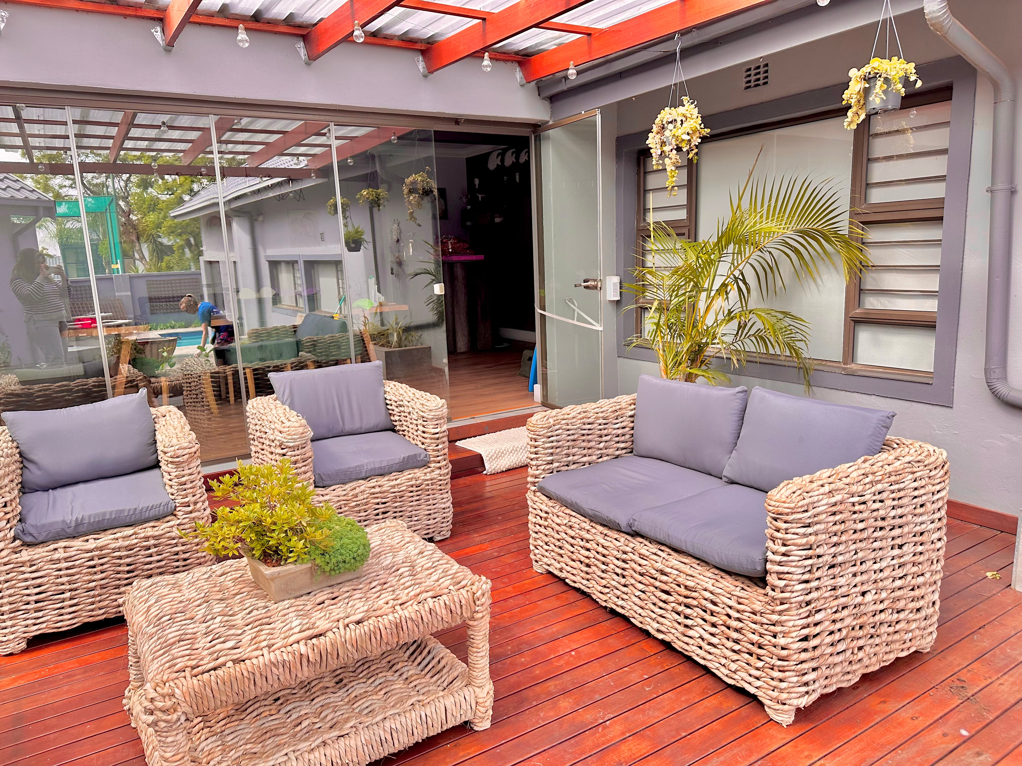 A grey cushion wicker lounge suite that is a double seater and 2 single seaters with a coffee table